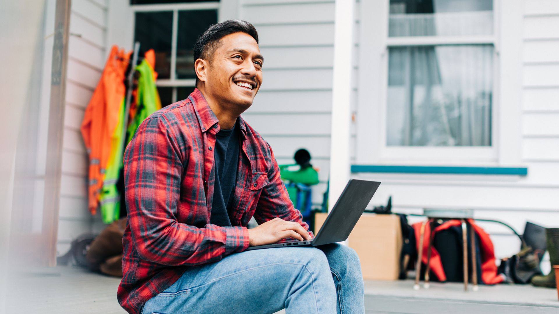 Young Māori man using his laptop on his porch — representing the ease of accessing Coverfy’s insurance and KiwiSaver advice online from home