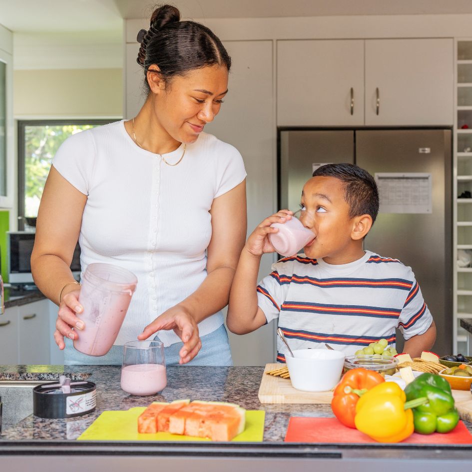 Young Māori mother making smoothies with her son in a bright kitchen — representing whānau wellbeing and everyday protection with Coverfy